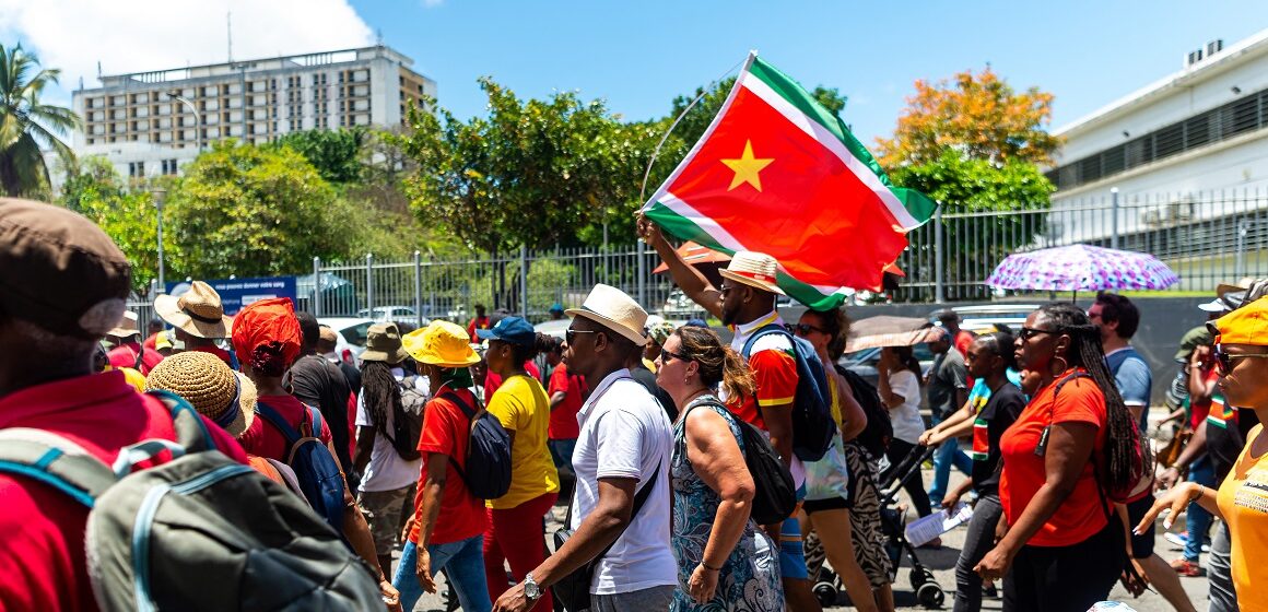 Des manifestants, brandissent le drapeau régional guadeloupéen, lors d'un défilé du 1er Mai (Fête du Travail), le 1er mai 2023. Photo : Lara Balais / AFP